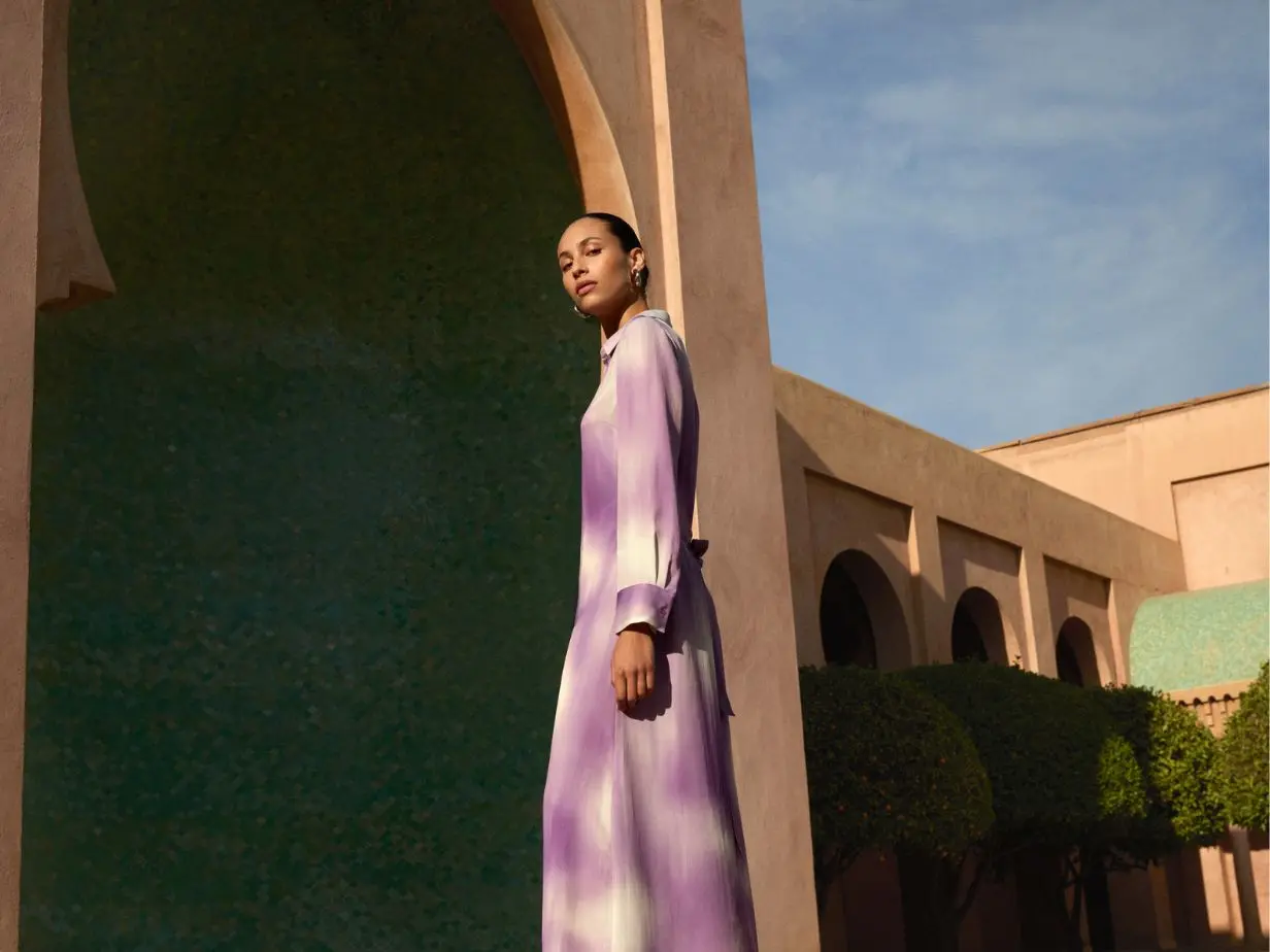 A woman wears a lilac and cream shirt dress