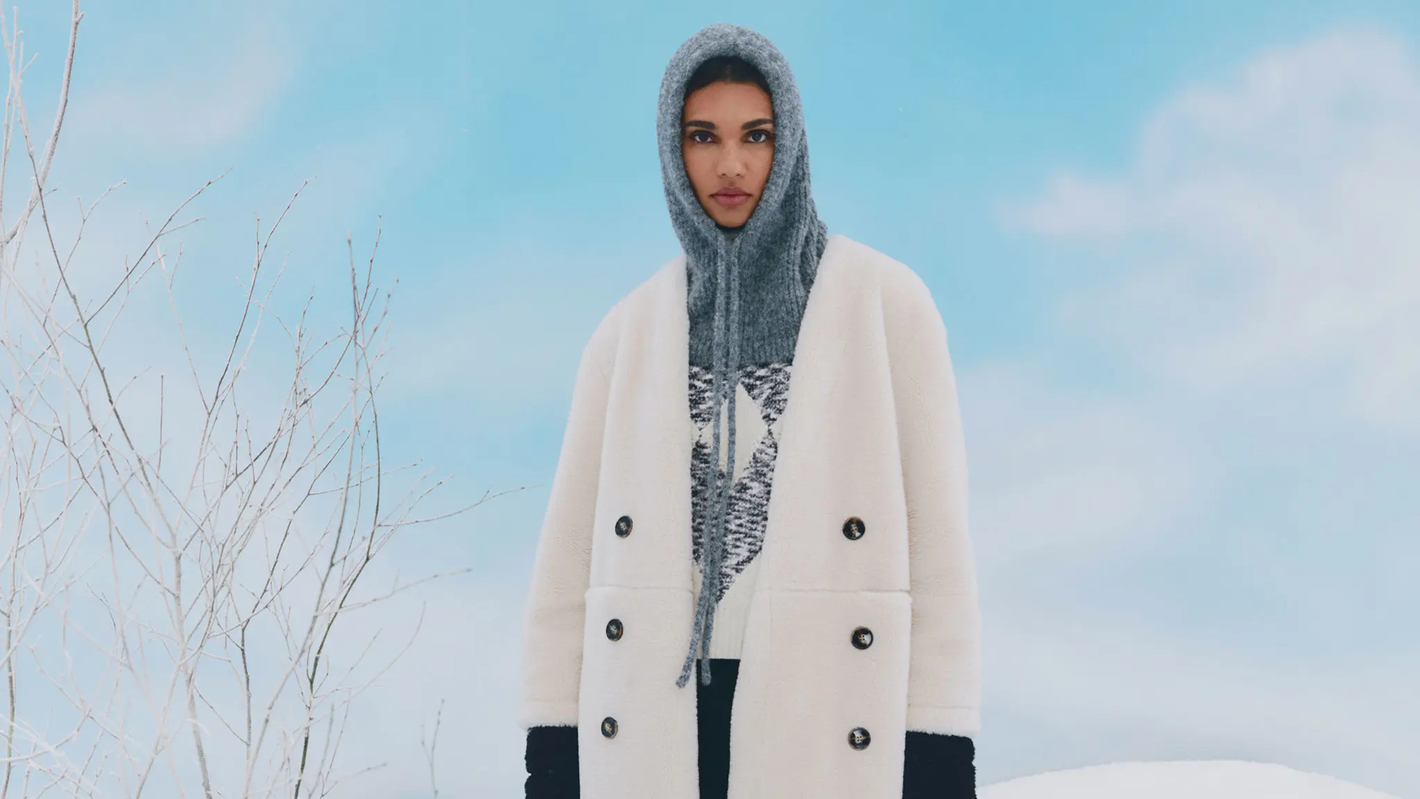 Woman wearing knitted grey hood, jumper and white coat