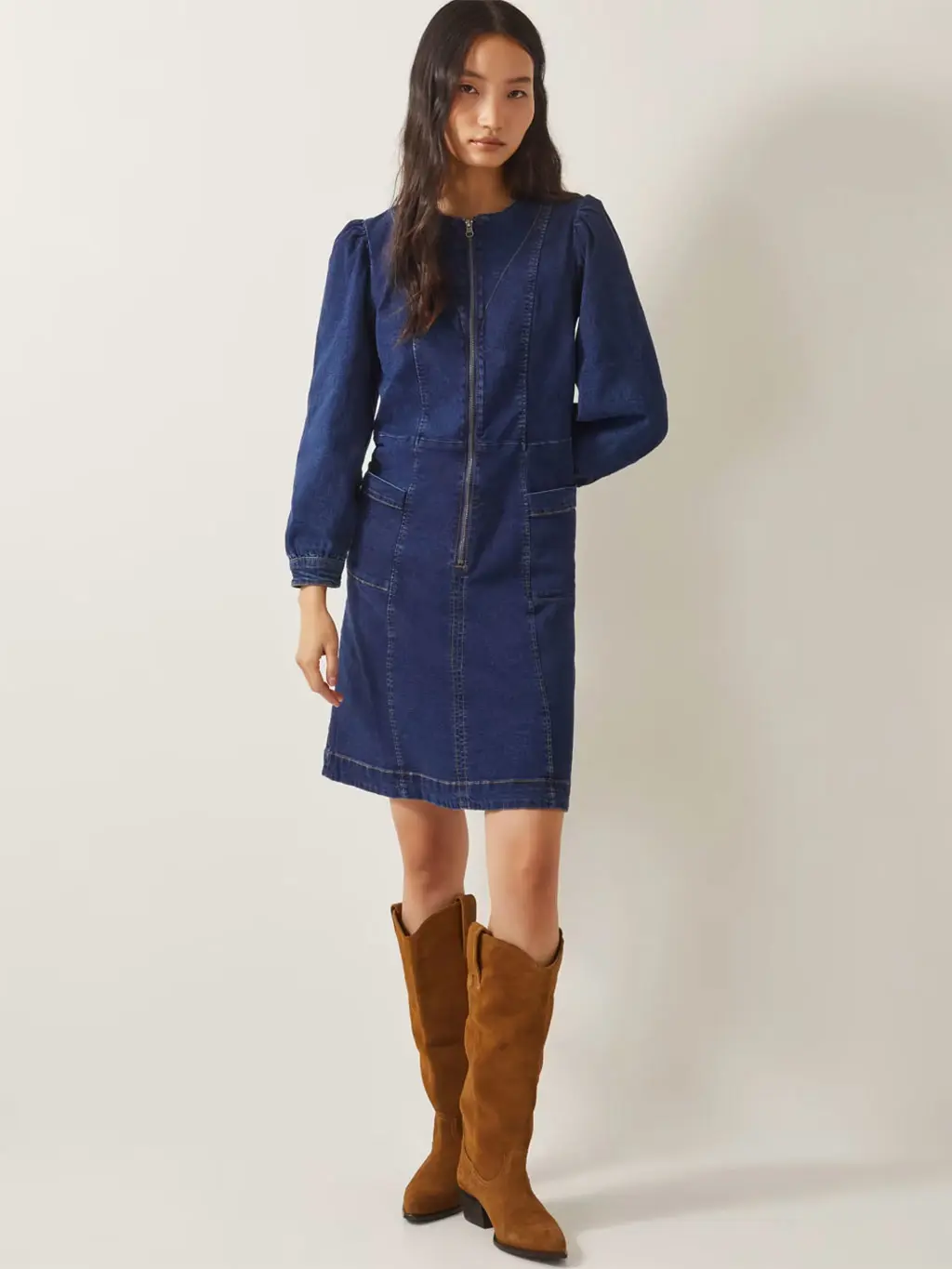 Woman wearing a denim mini dress with brown suede knee-high cowboy boots.