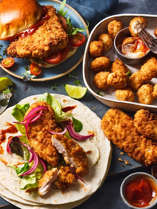 Chicken burger, strips, and nuggets in blue and grey bowls