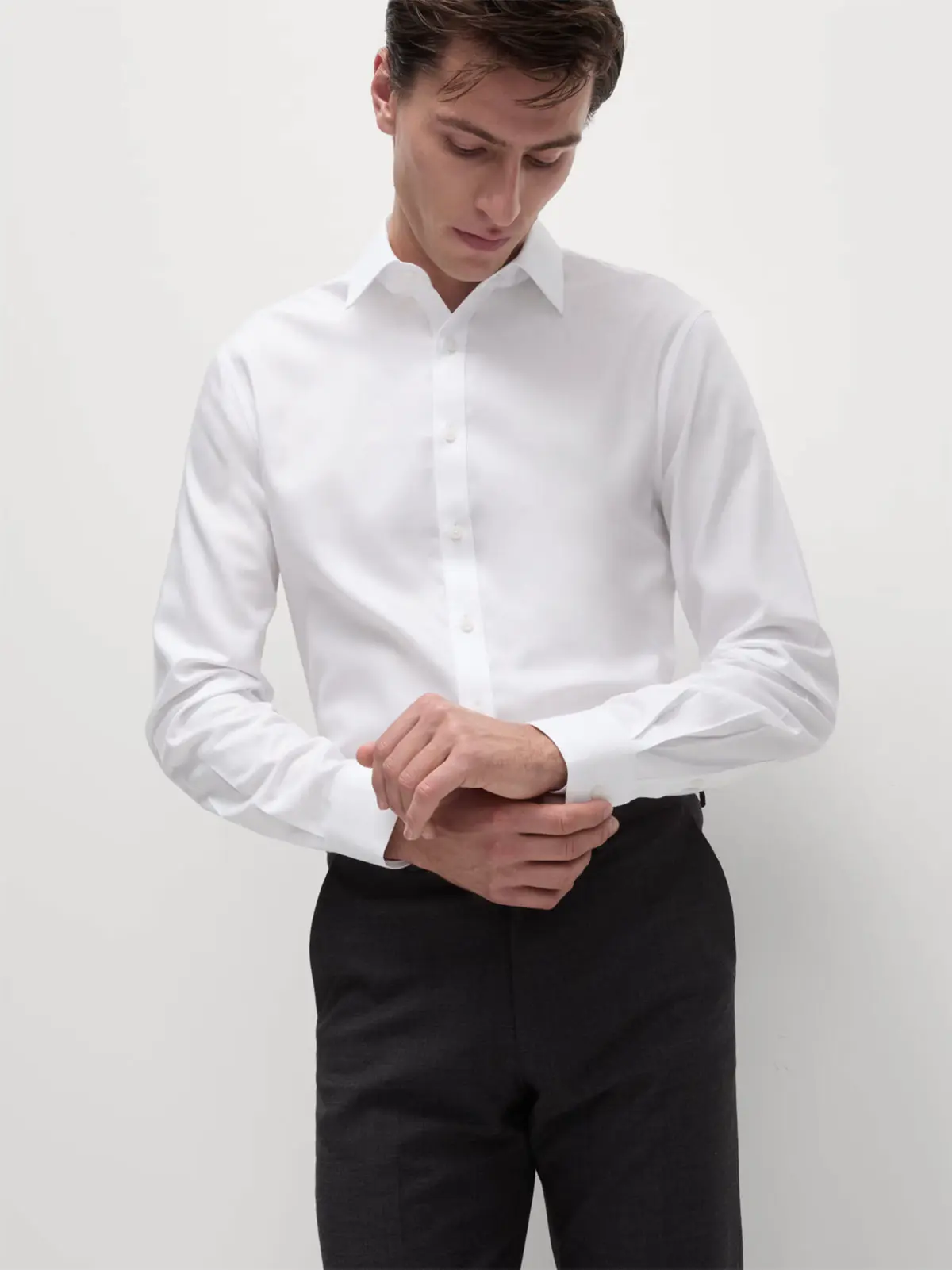 Man wearing white long sleeve shirt tucked into smart black trousers 