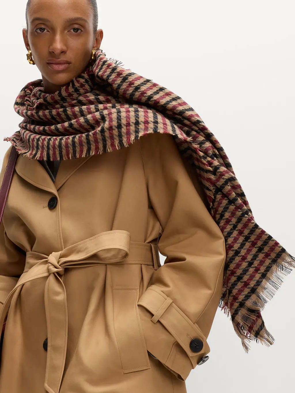 Woman wearing a checked scarf over a trench coat