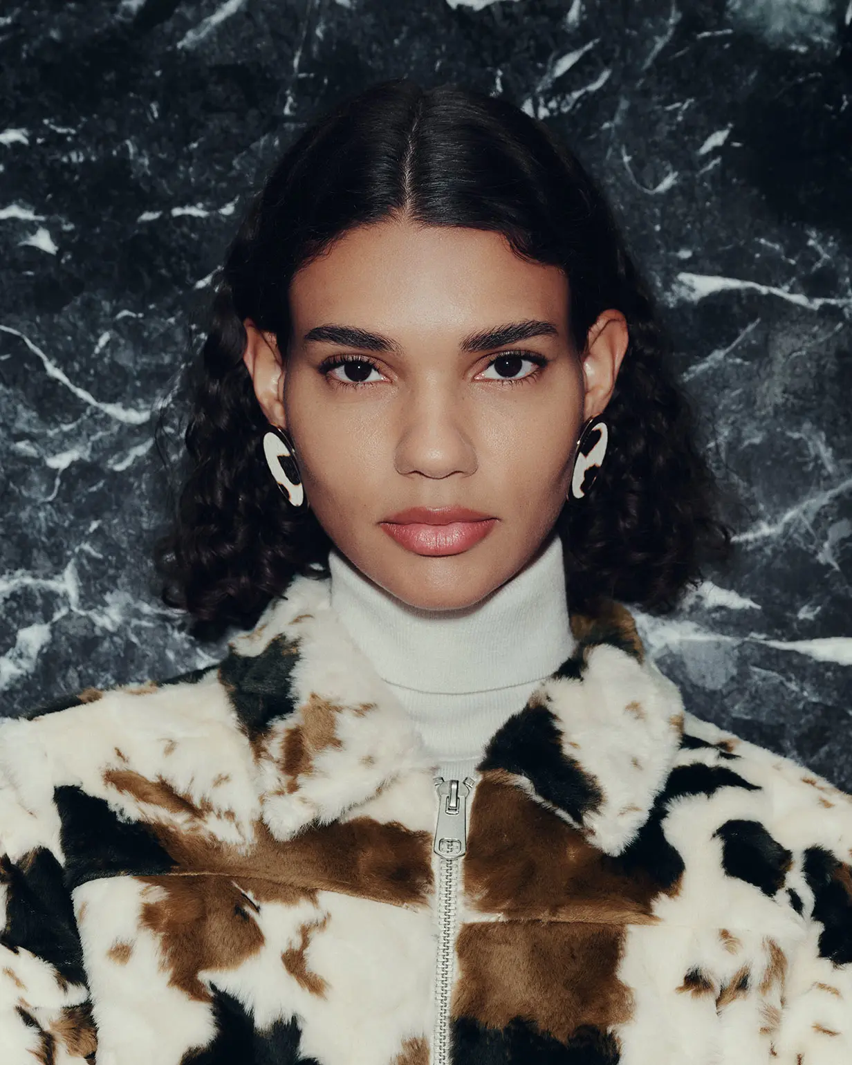 Woman wearing cow-print faux fur jacket and cream roll-neck jumper
