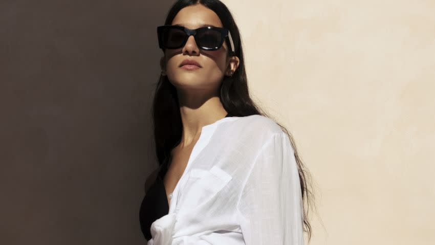 Woman wearing white linen shirt and sunglasses. Visit the holiday shop