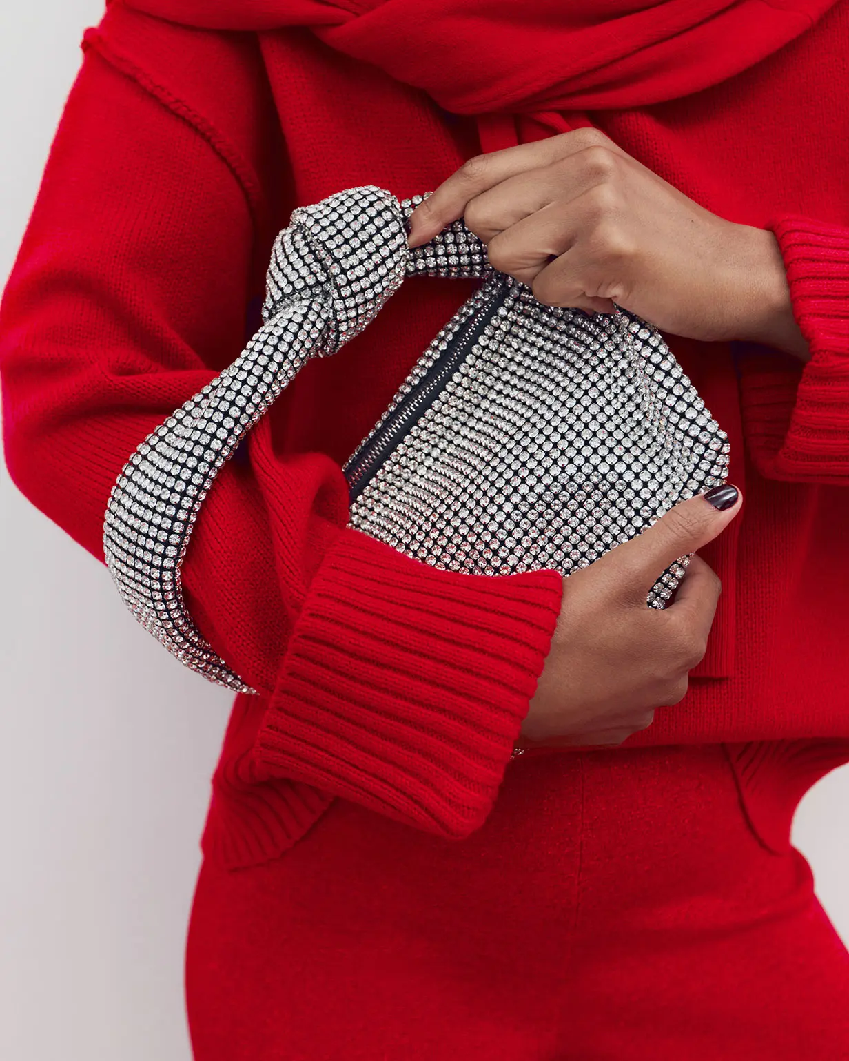 Woman wearing red jumper holding metallic bag
