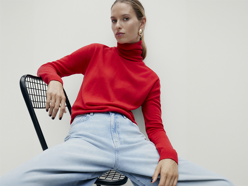 Woman wearing red poloneck jumper and light blue jeans