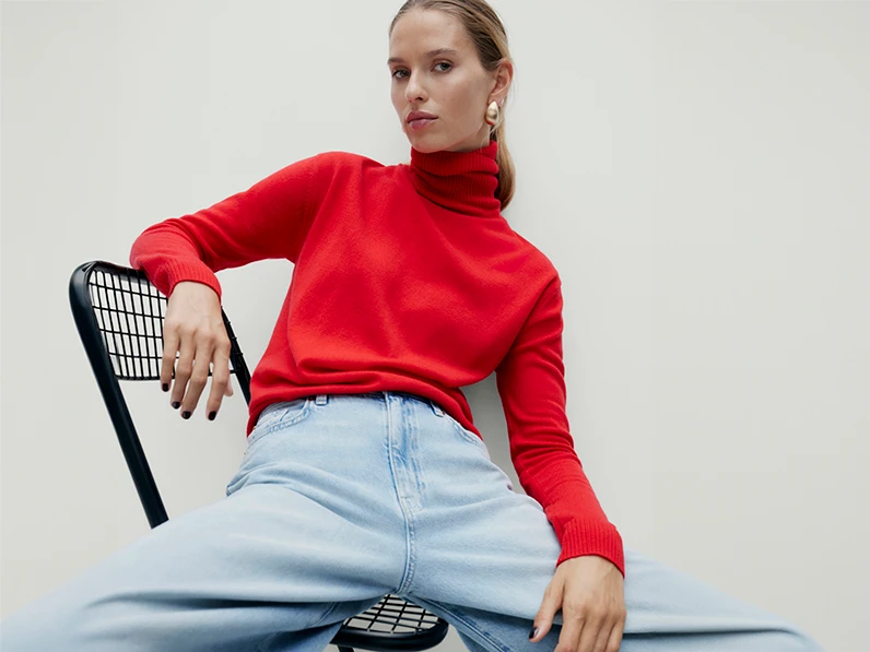 Woman wearing red poloneck jumper and light blue jeans