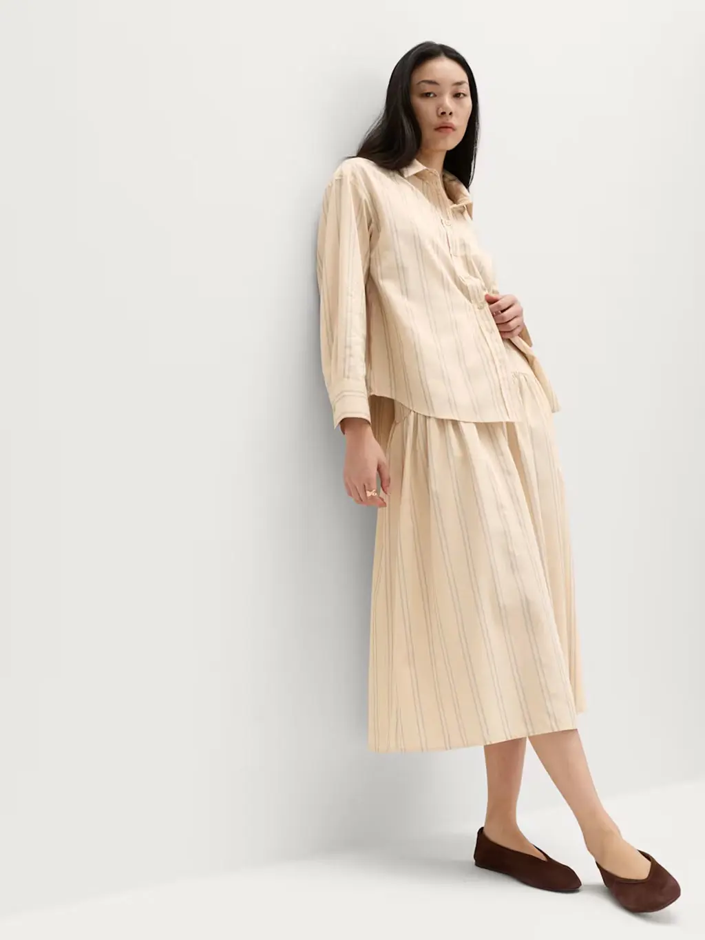 Woman wearing a yellow striped shirt with a matching skirt and brown ballet pumps