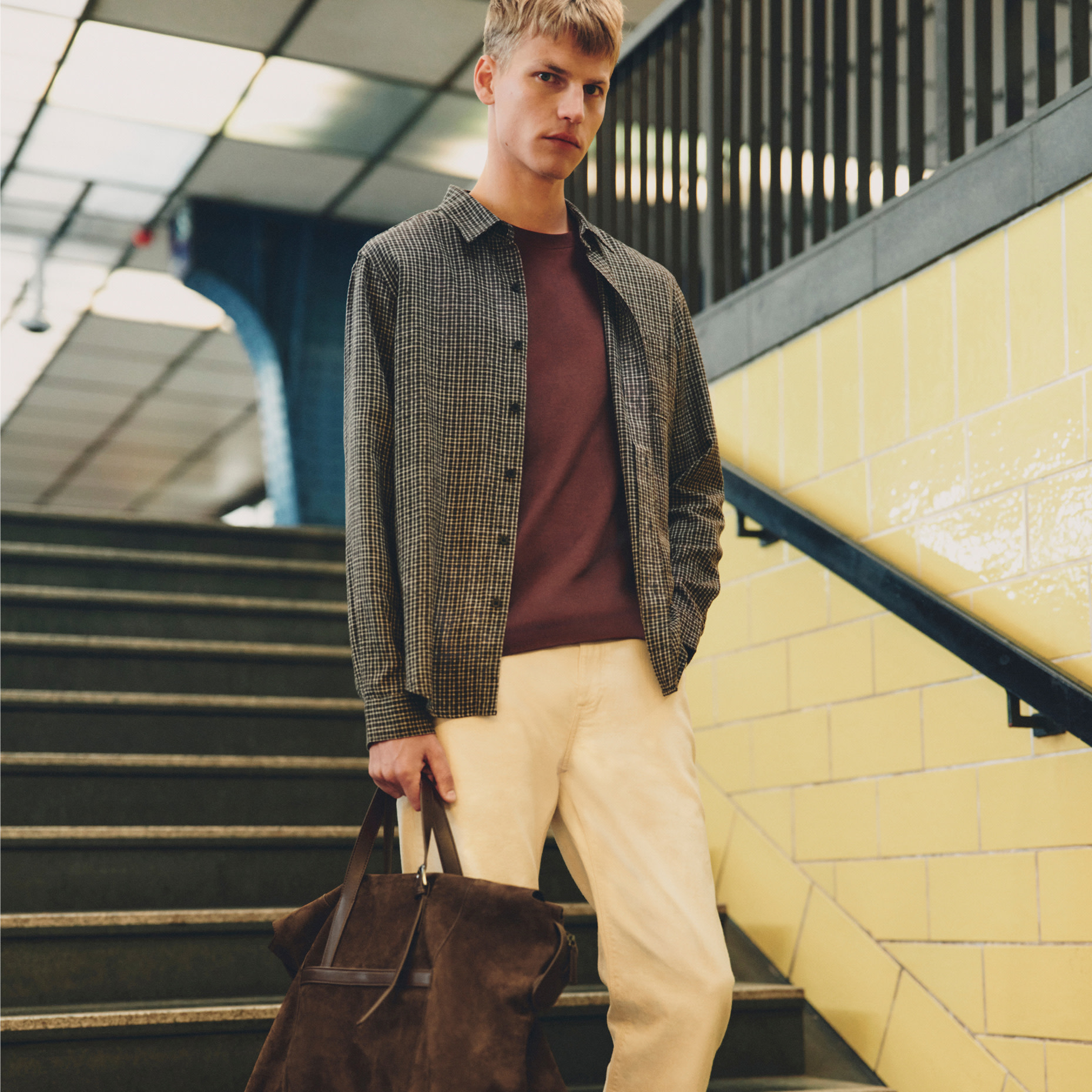 Man wearing checked shirt over red T-shirt and neutral trousers