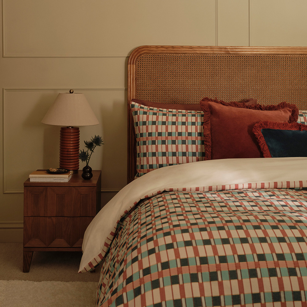 Bedroom scene with scalloped-edge bed, rattan lampshade and geometric bedding set