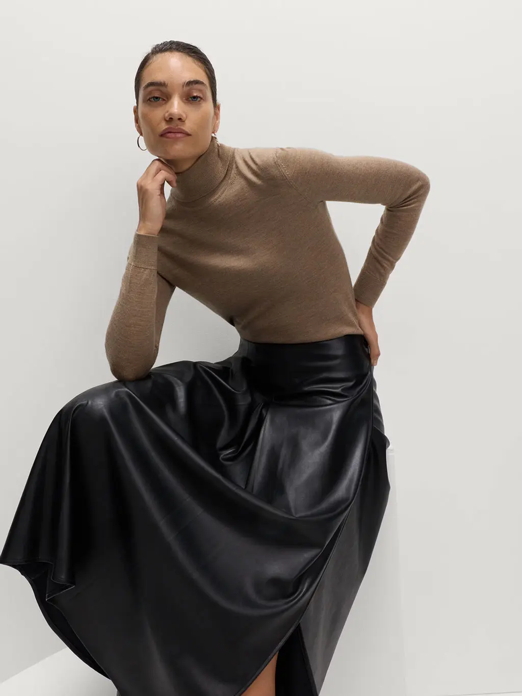 Woman wearing a brown high-neck top with a black leather skirt