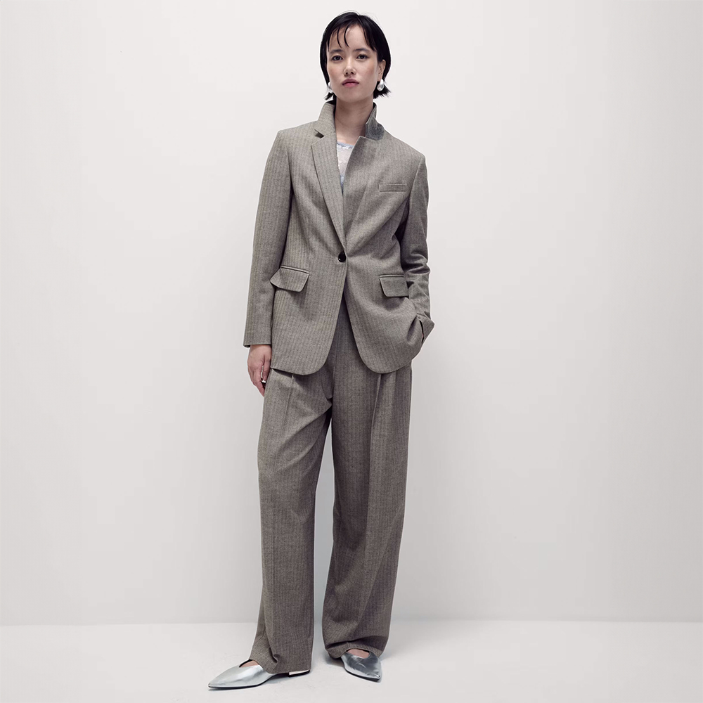 Woman wearing herringbone trouser suit and pointed silver flat shoes