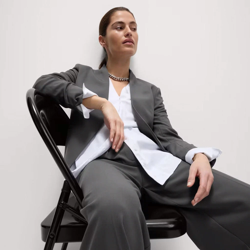 Woman wearing grey collarless trouser suit and white shirt