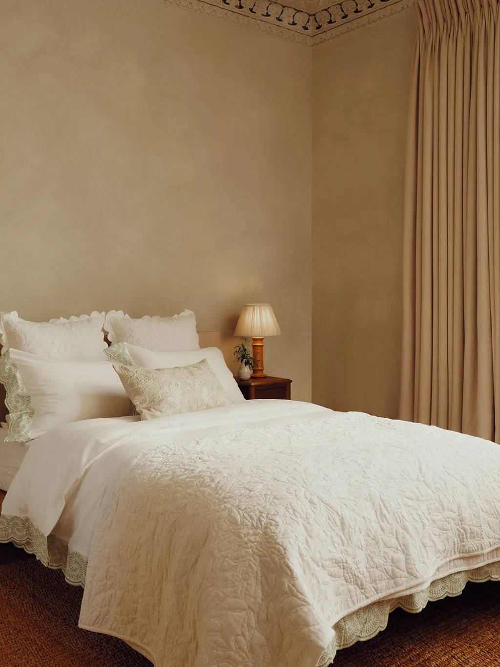 Bed with neutral bedding against a neutral backdrop