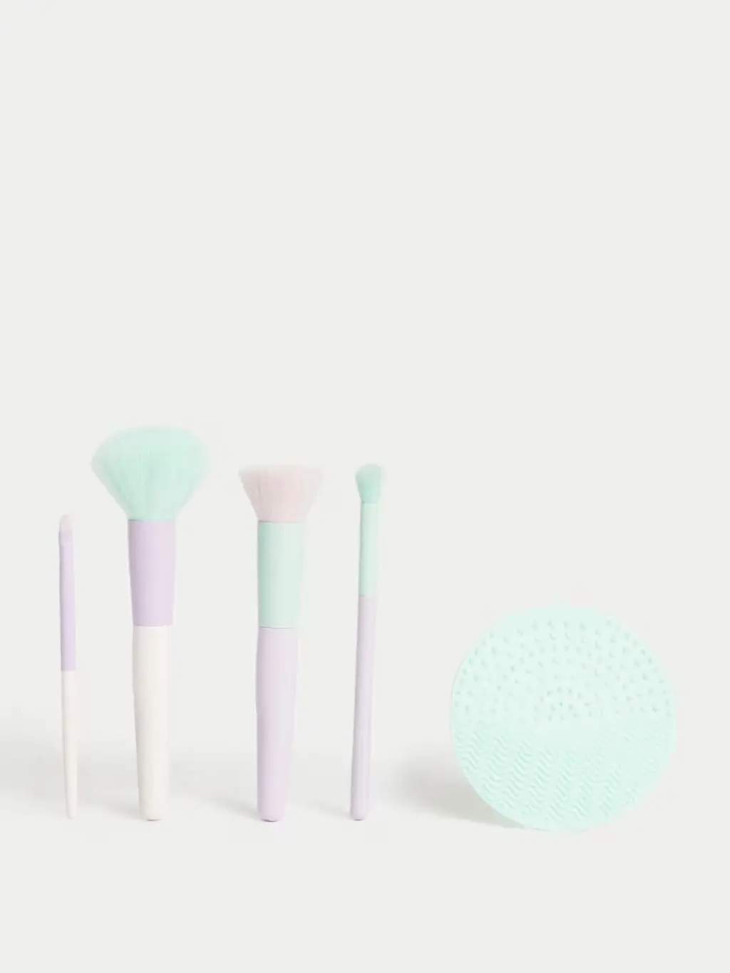 A line up of pastel makeup brushes and a silicon cleansing pad