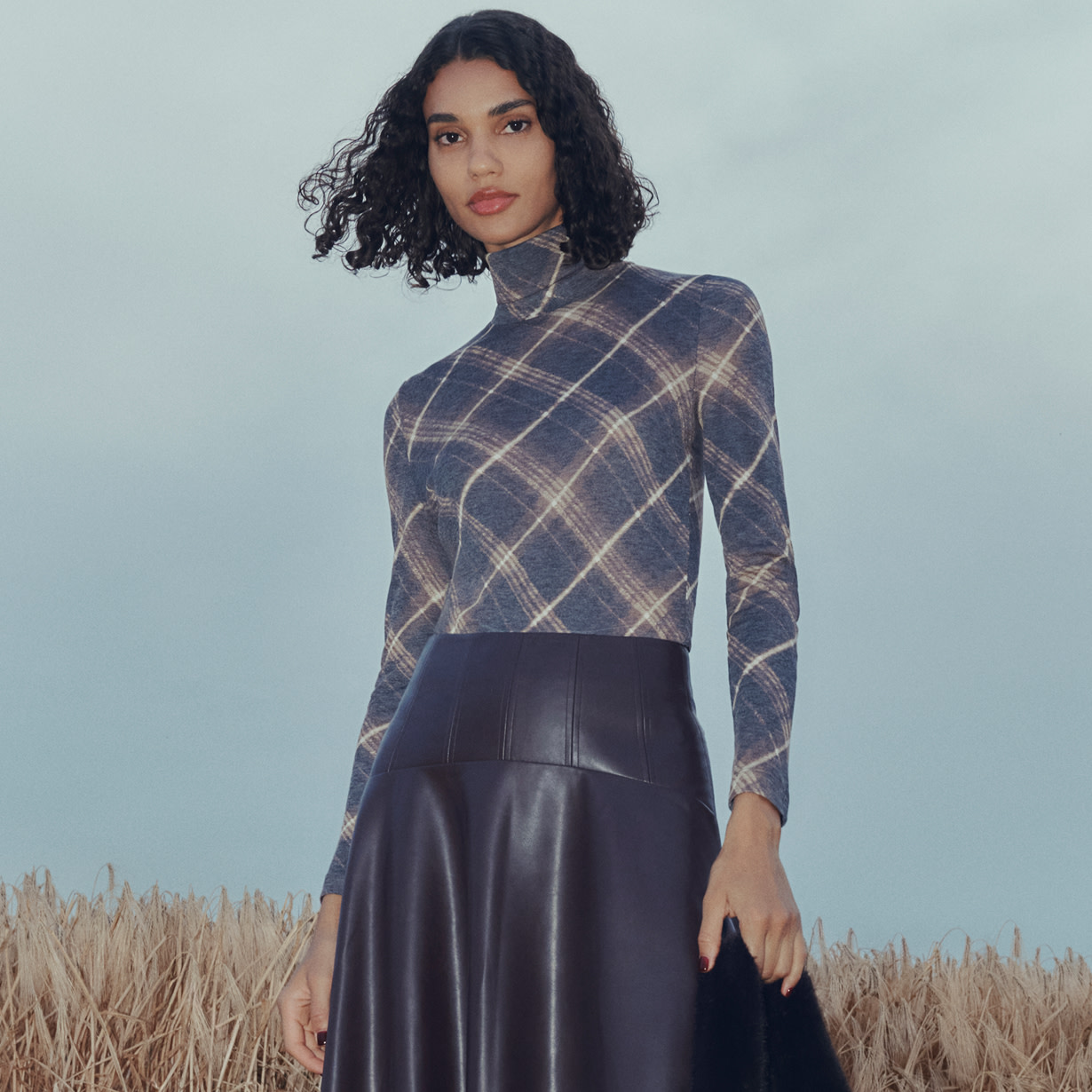 Woman wearing checked top and black leather midi skirt
