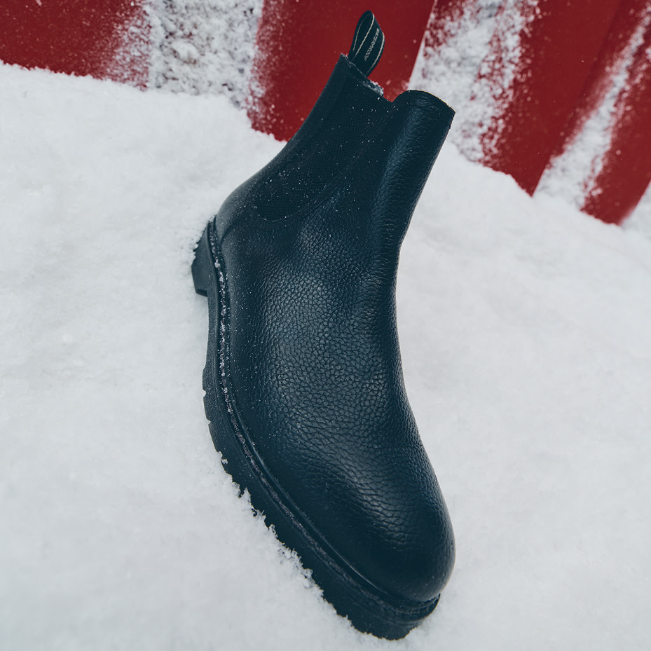 A single black Chelsea boot in the snow