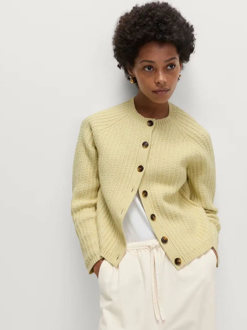 Woman wearing a yellow cardigan with a white T-shirt and linen trousers