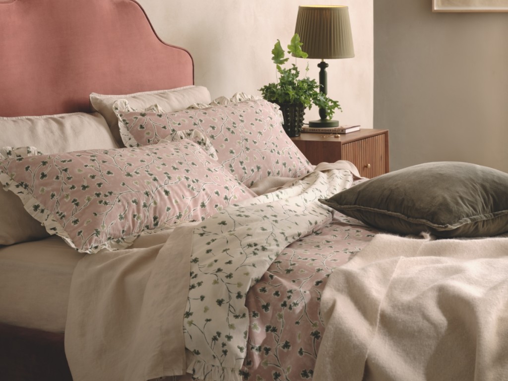 Bed with pink headboard and light pink floral print bedding. Shop duvet covers