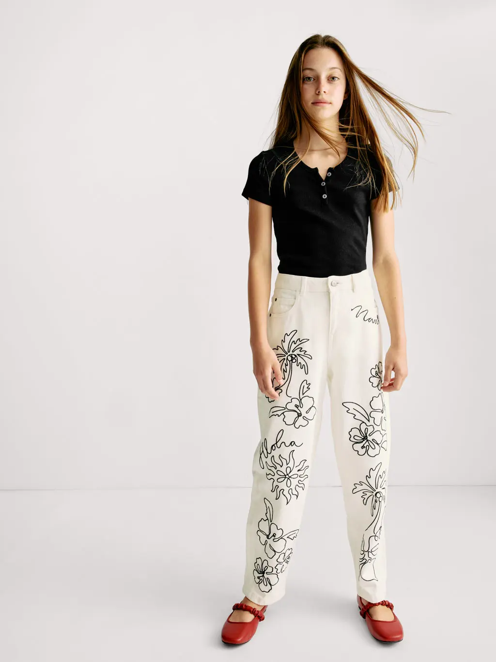 Girl wearing a black top and white embroidered jeans