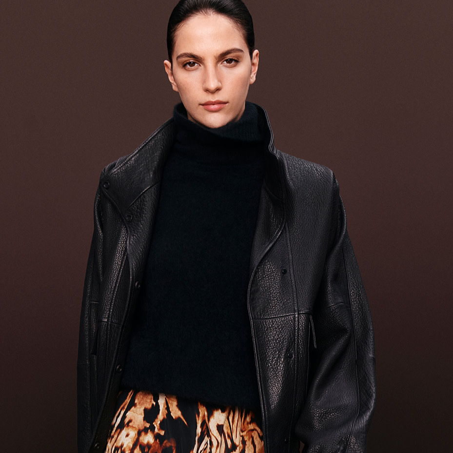 Woman wearing black leather jacket over black jumper and printed skirt
