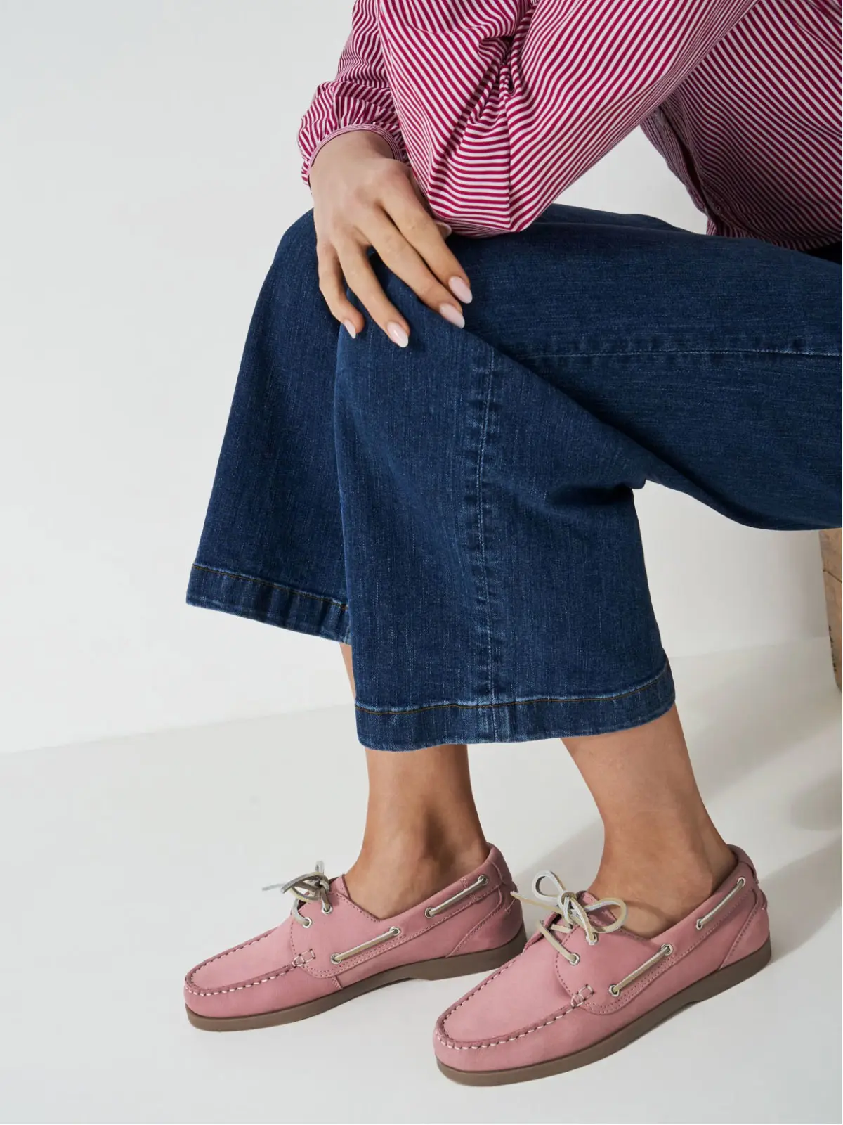 Close up of woman wearing pink striped shirt, blue jeans and pink boat shoes