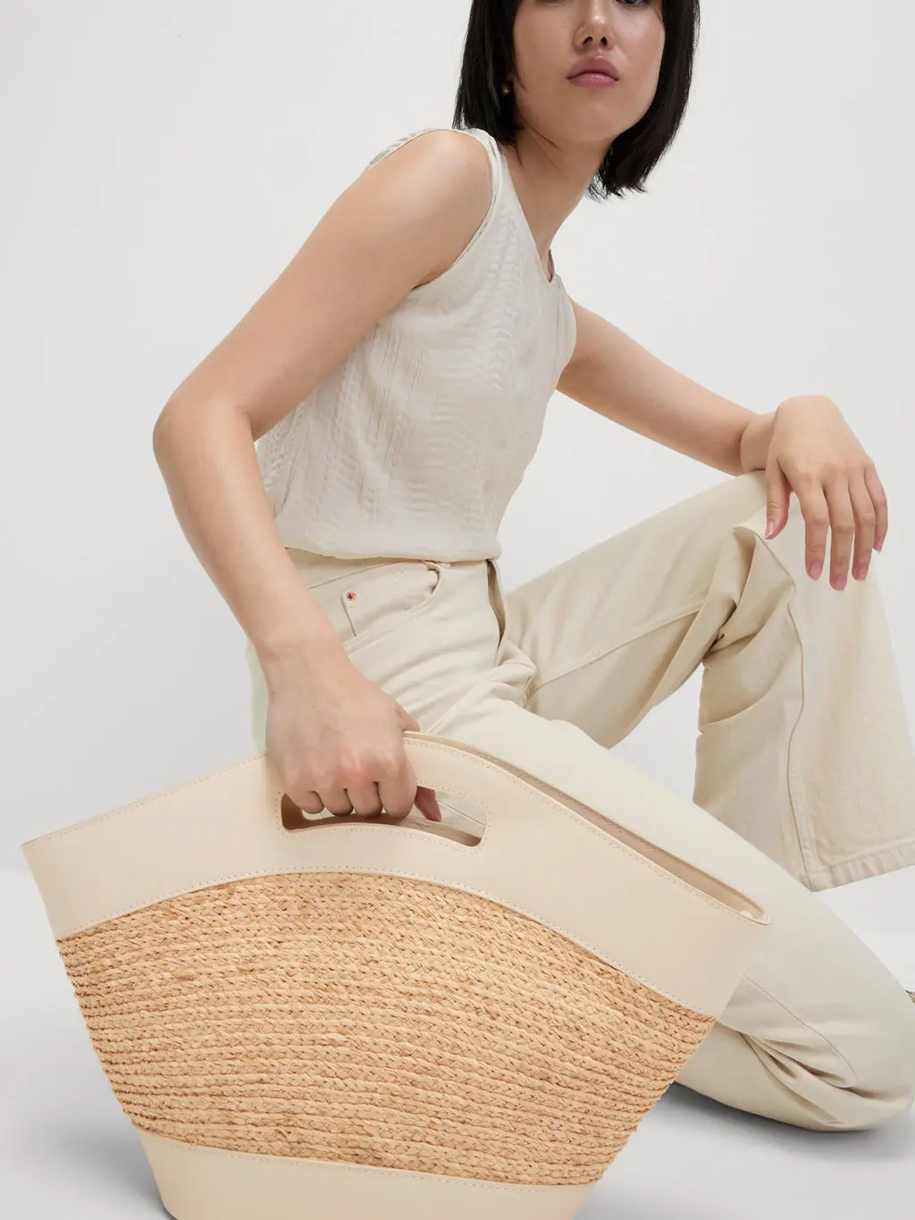 Woman holding straw beach bag with top handles