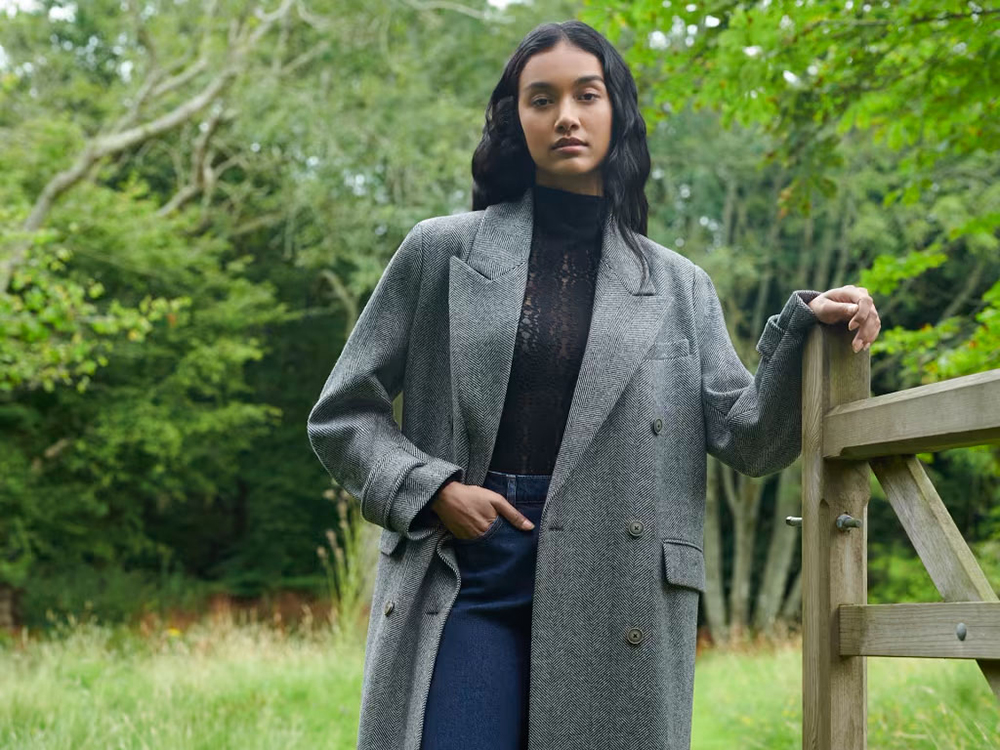 Woman wearing a countrycore outfit standing by a fence in a field