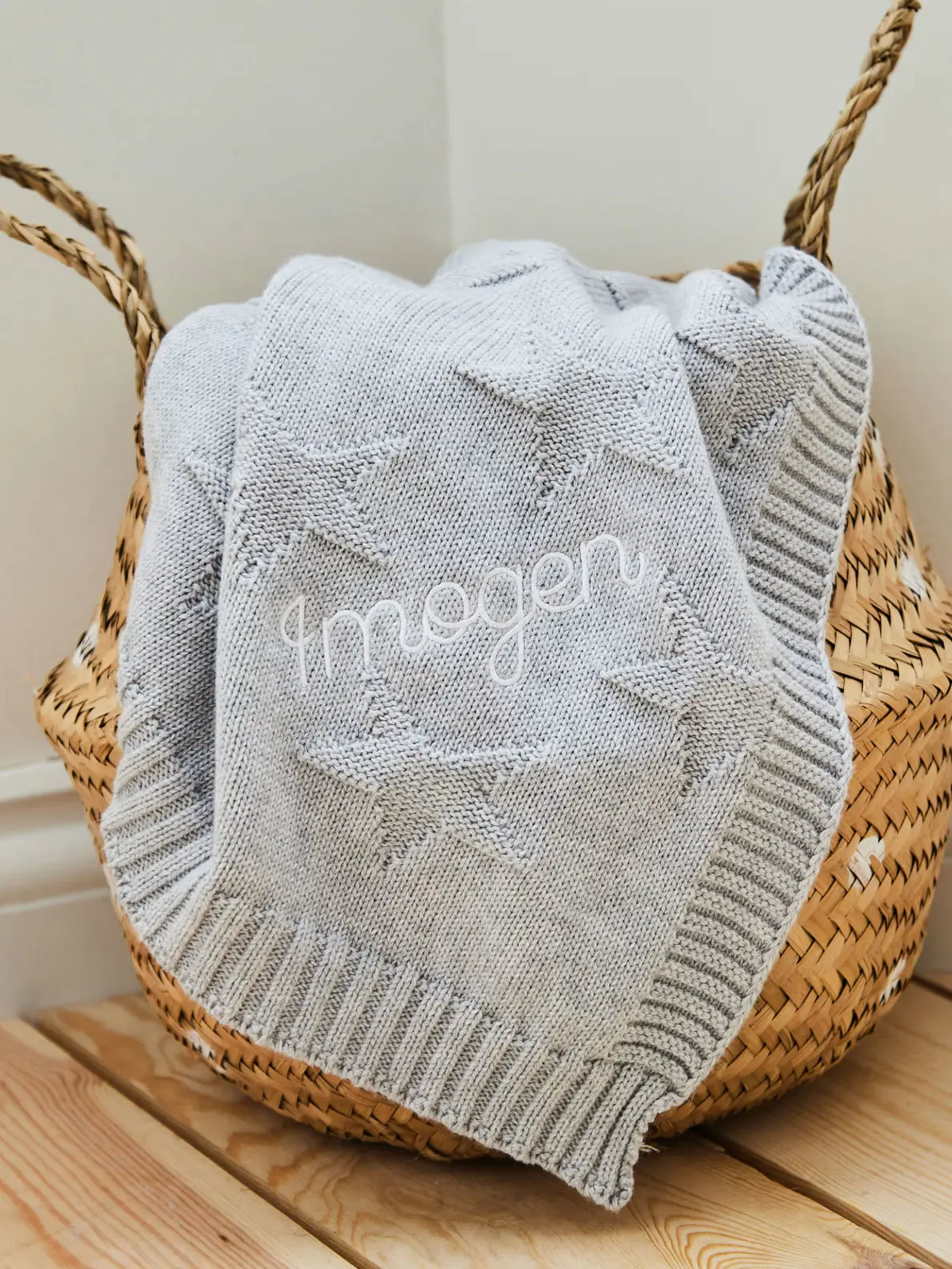 Knitted blanked draped over basket with name 'Imogen' embroidered in white