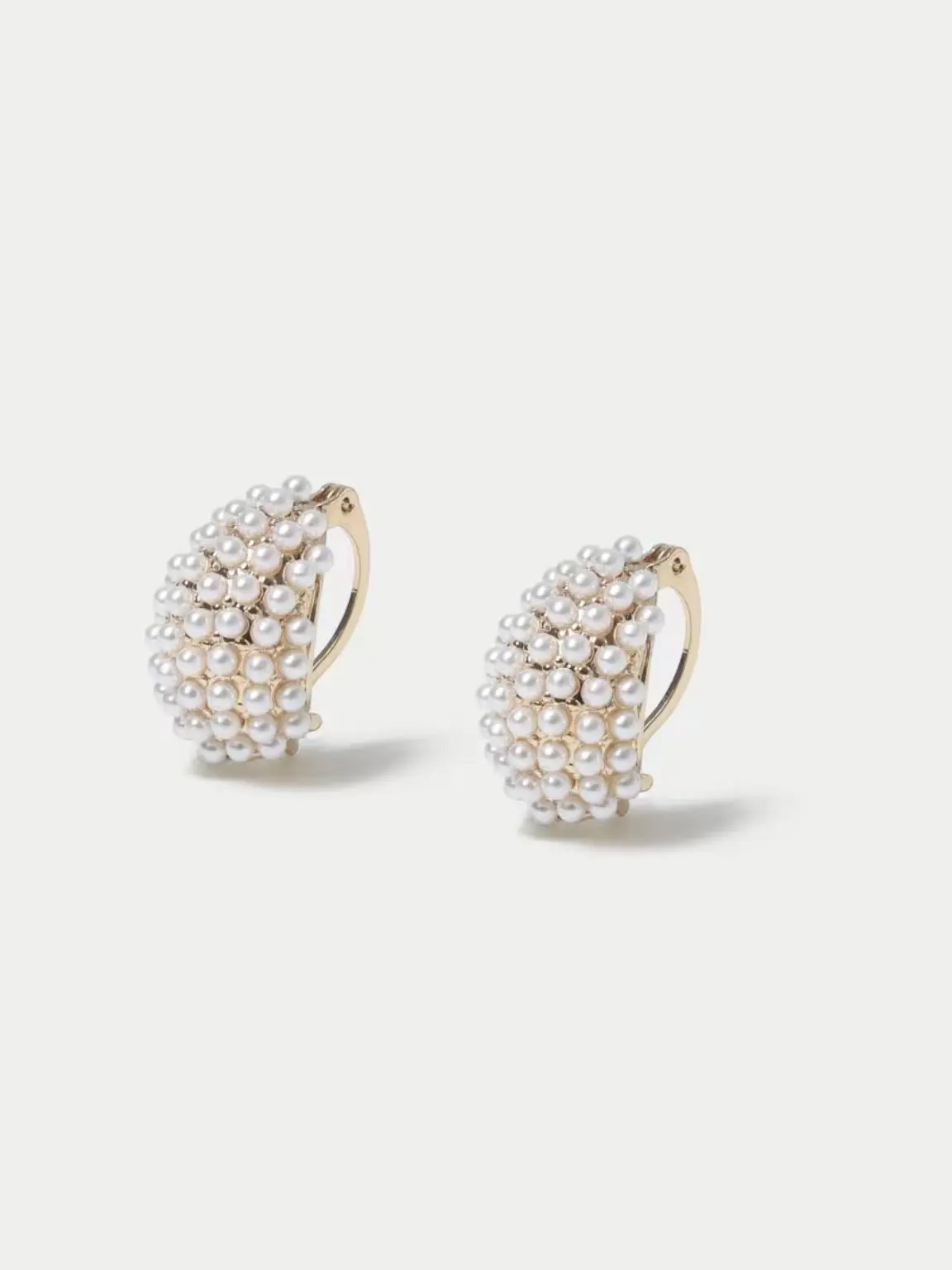 A cutout of pearl earrings against a light grey background