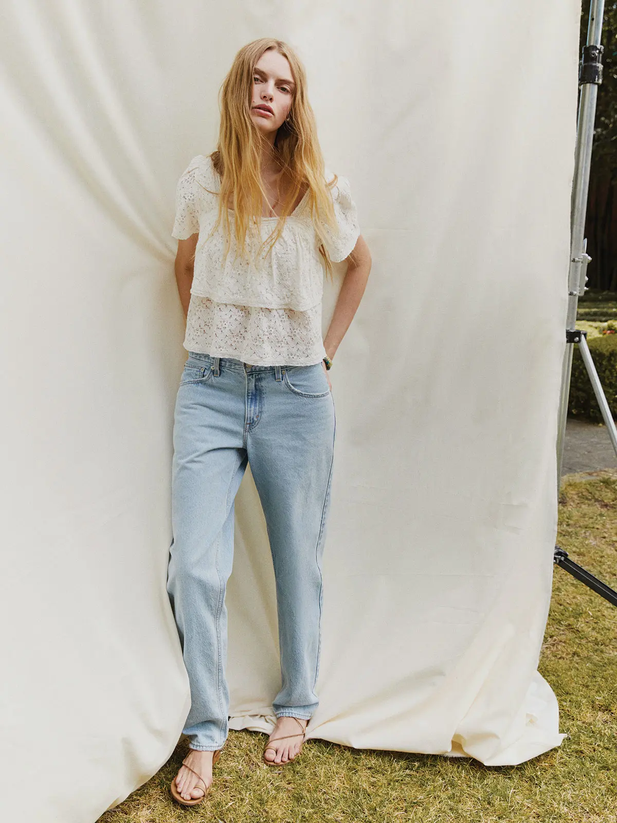 Woman wearing floaty white top, blue Levi's jeans and sandals