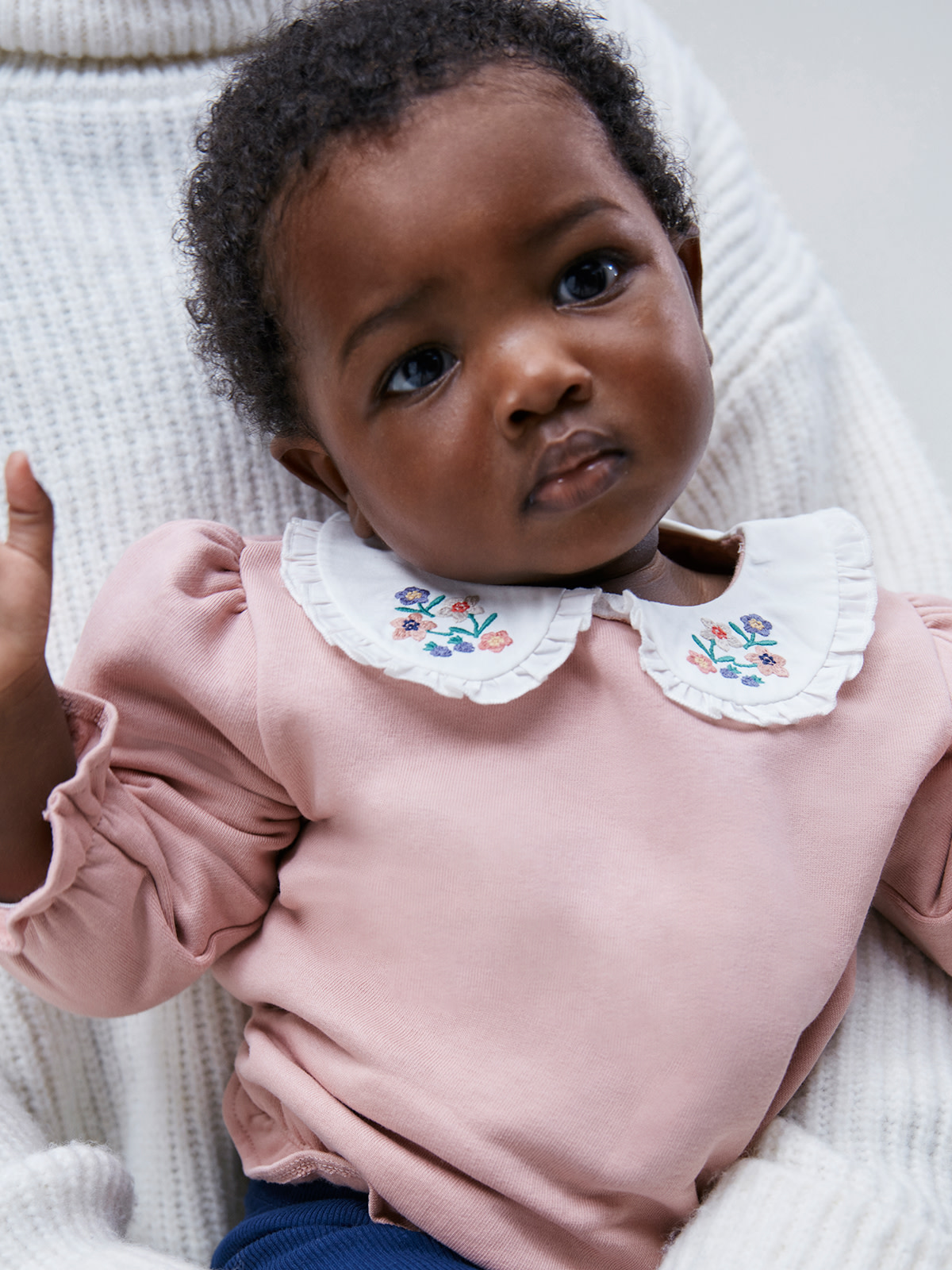 Baby wearing pink jumper. Discover gift ideas for new parents