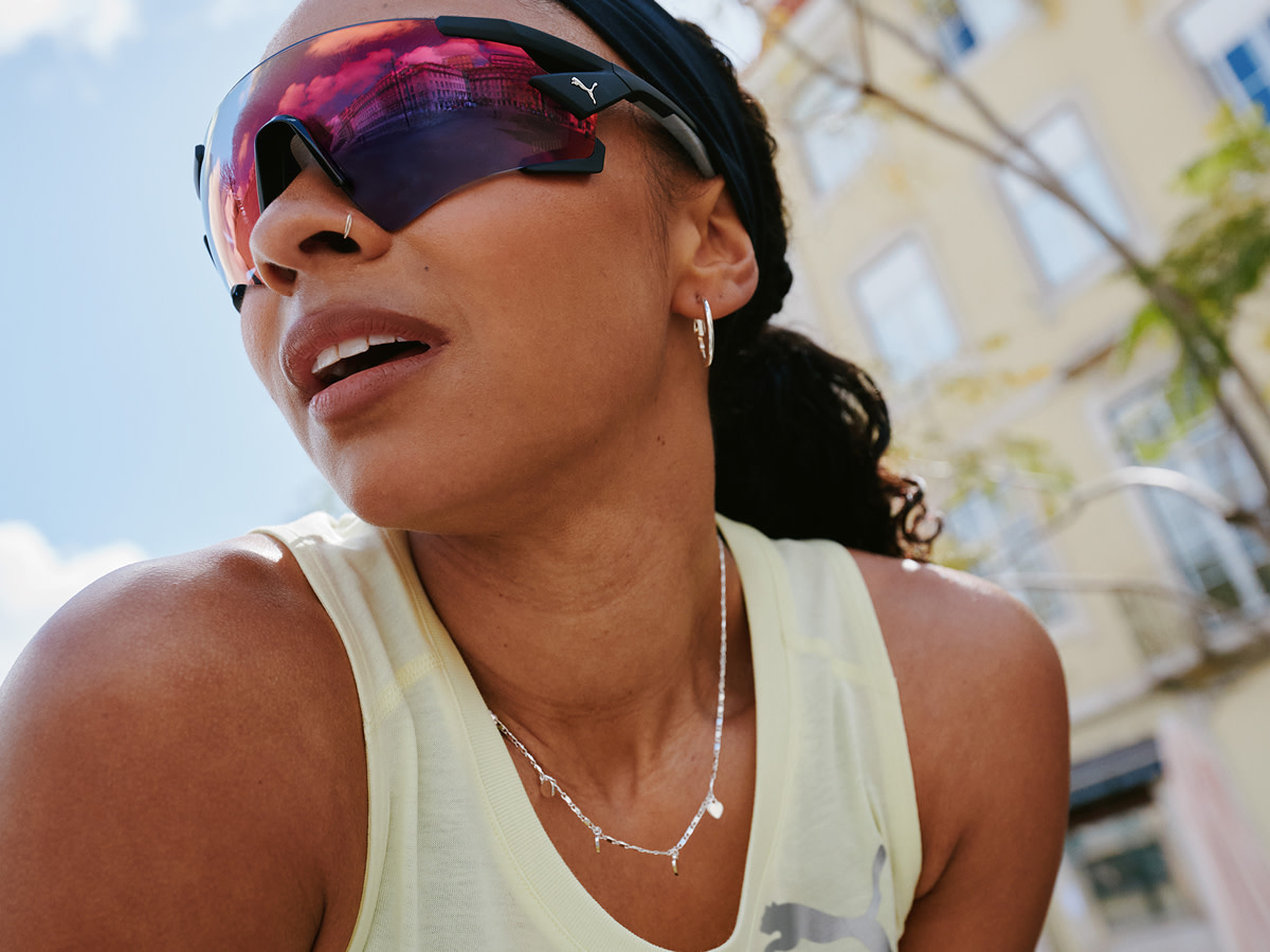 Woman wearing Puma sunglasses and cream sports vest
