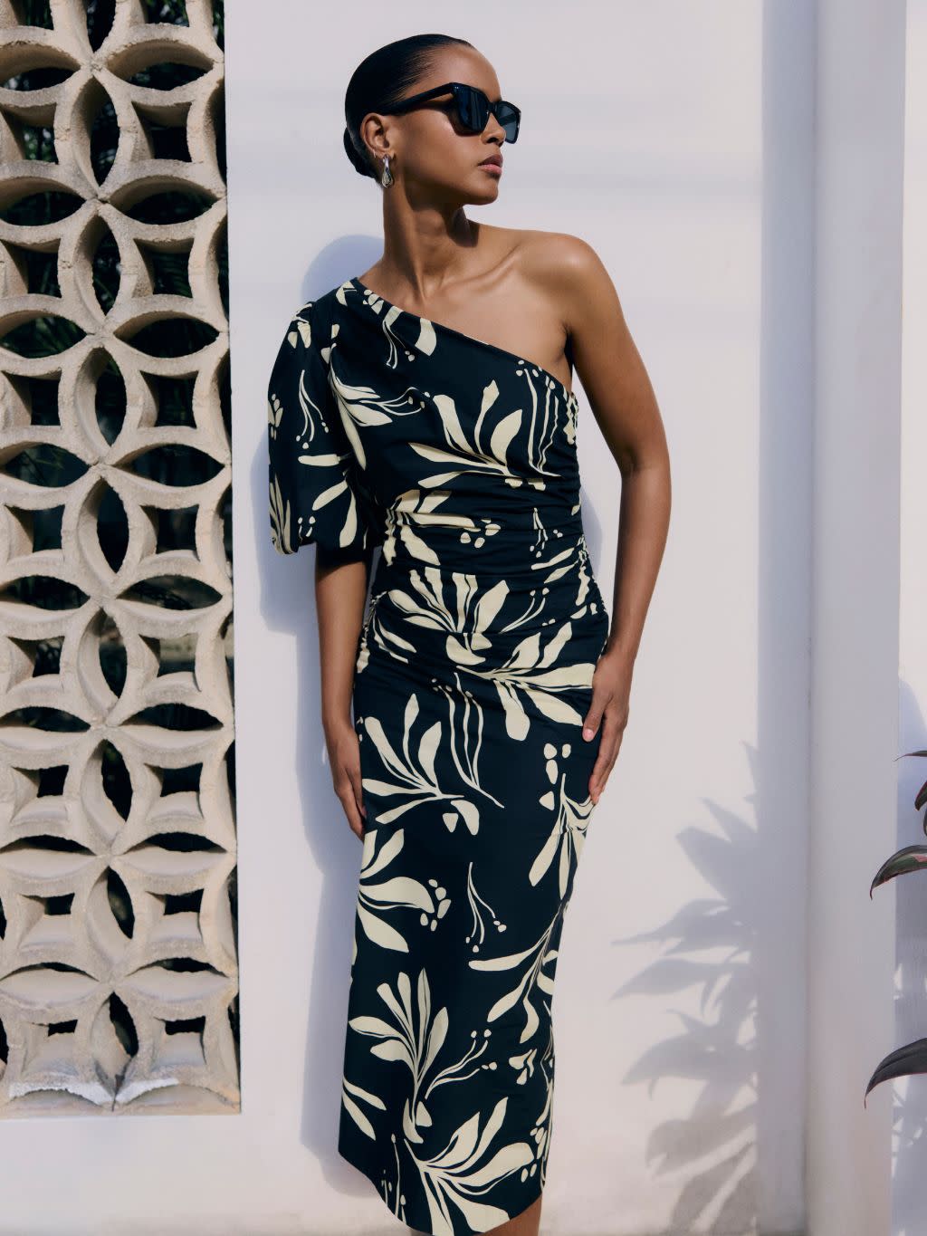 A woman wears a one shoulder patterned midi dress