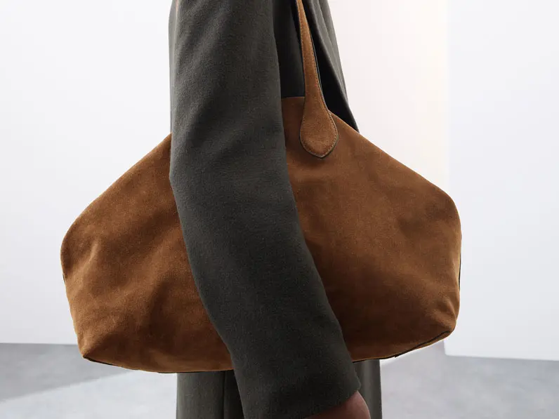 Woman holding brown suede tote bag