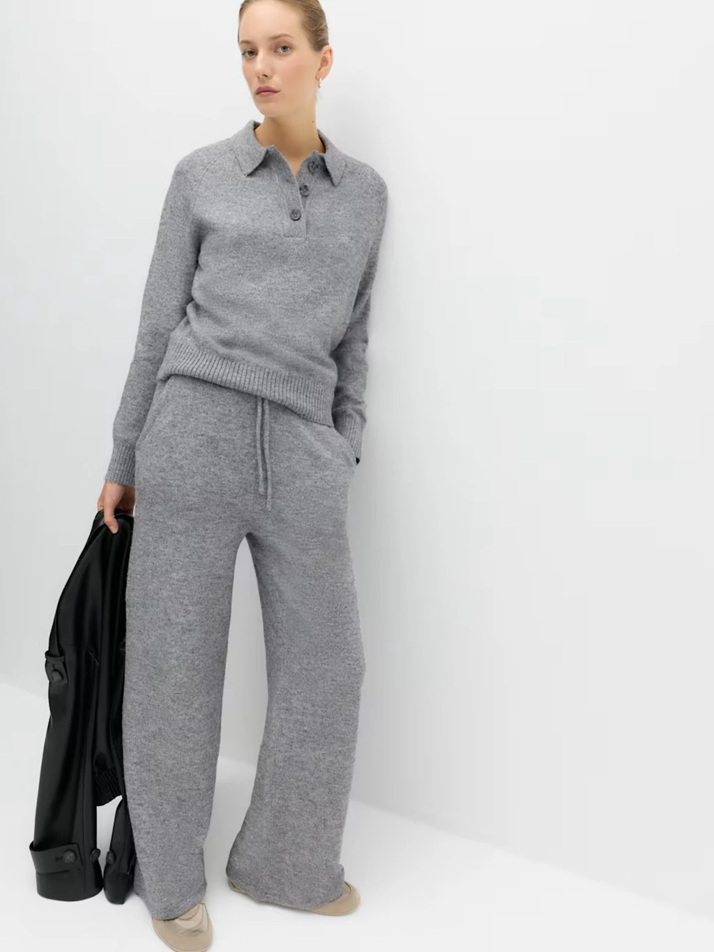 Woman wearing a pair of grey joggers, grey sweatshirt and beige trainers.