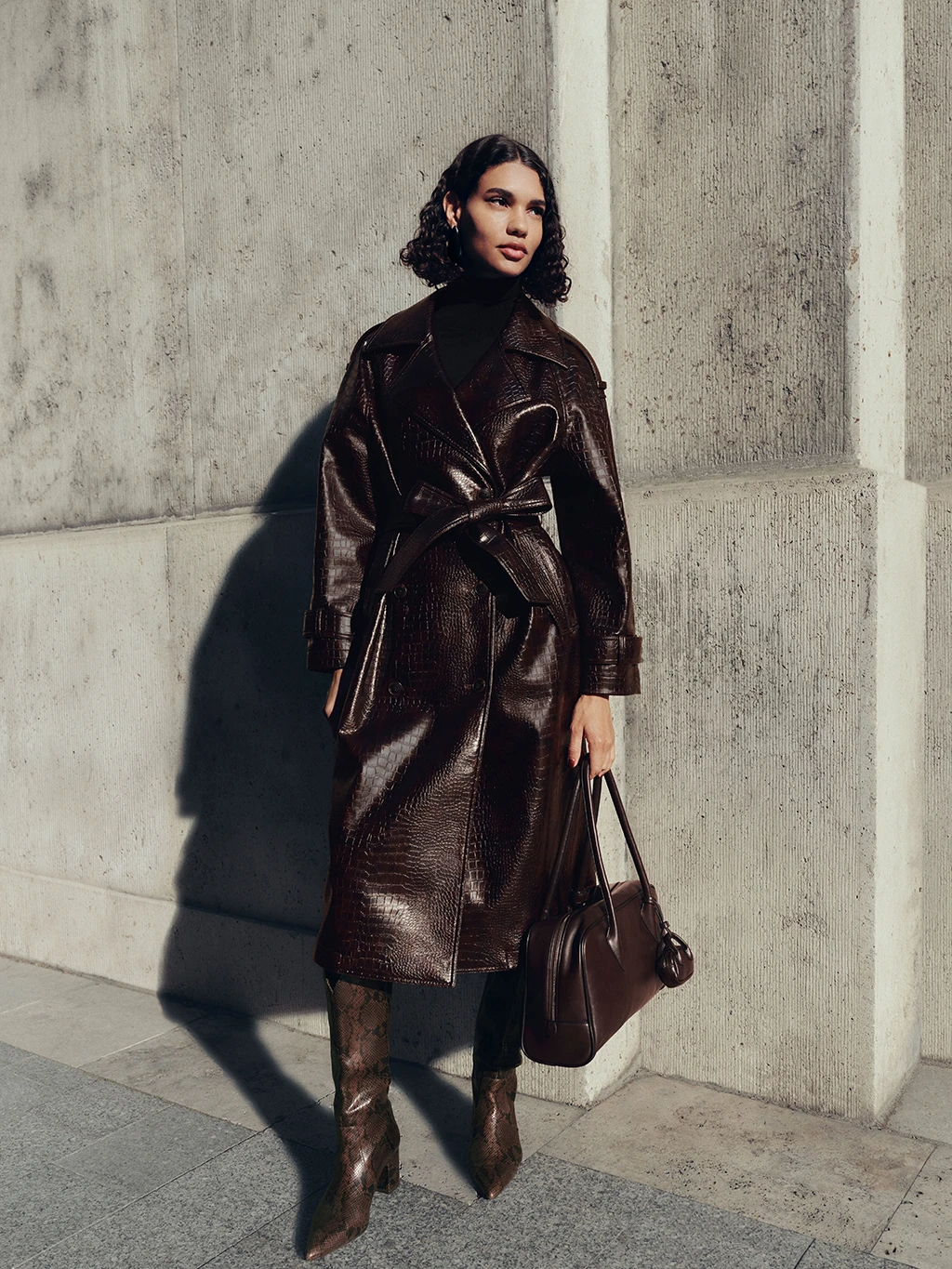 Woman wearing brown mock-croc coat with knee-high boots