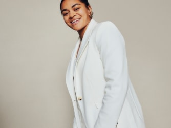 Member of the women’s football team wearing white blazer and white trousers