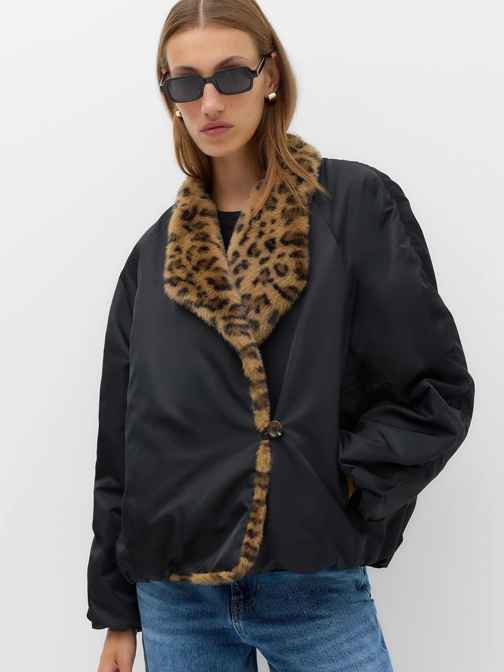 Model in a black satin bomber jacket with a leopard print faux fur collar.