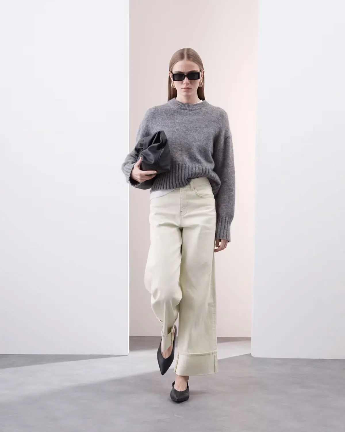 Woman wearing grey jumper and off-white wide-leg jeans