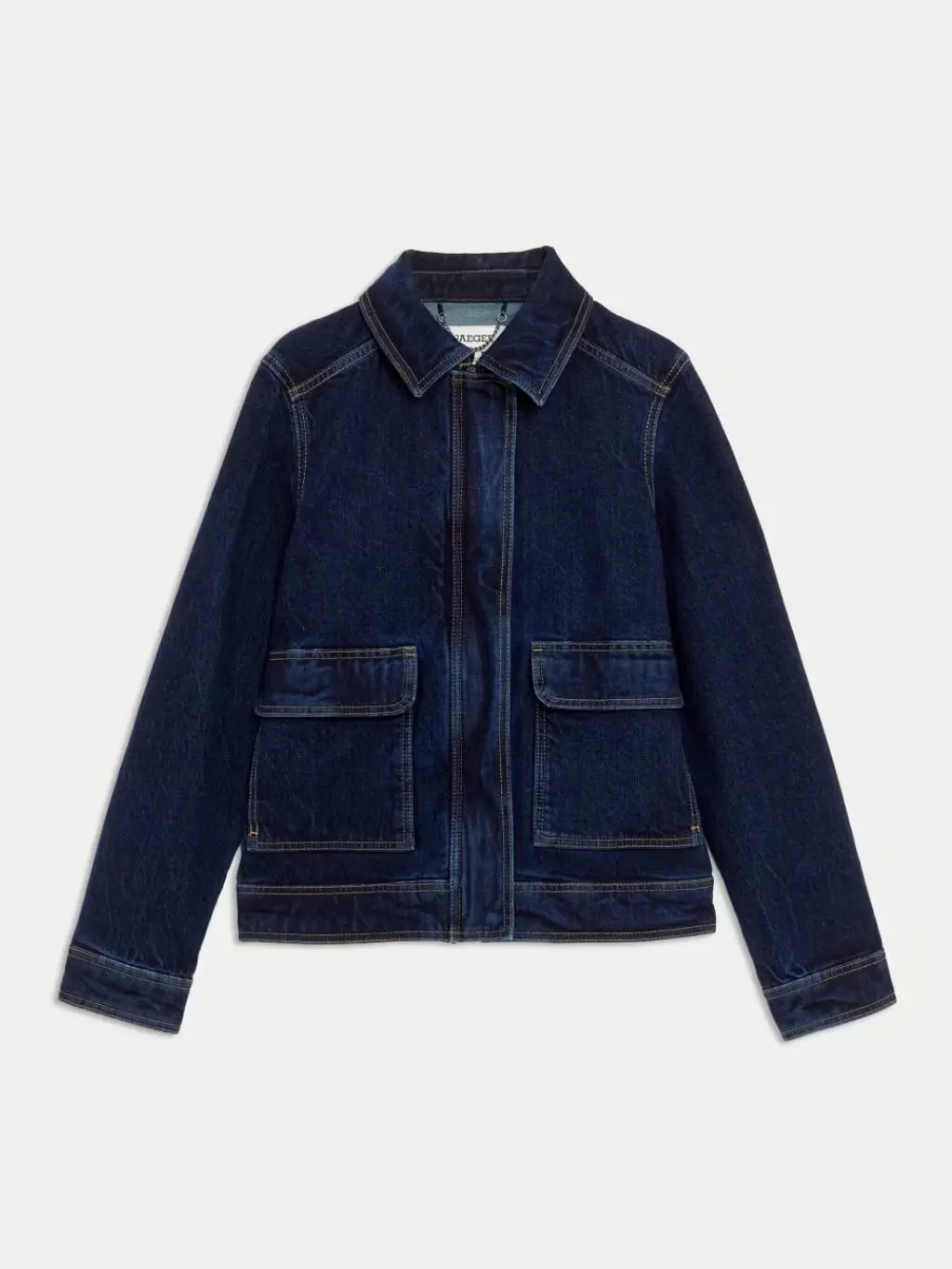 A cutout of a dark denim trucker jacket on a cream background