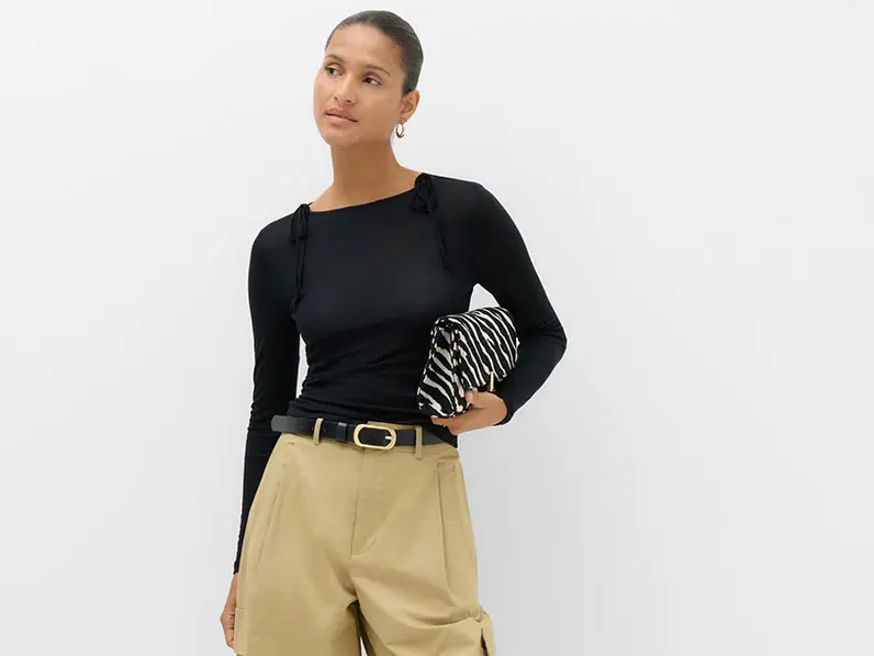 Woman in black top and tan trousers