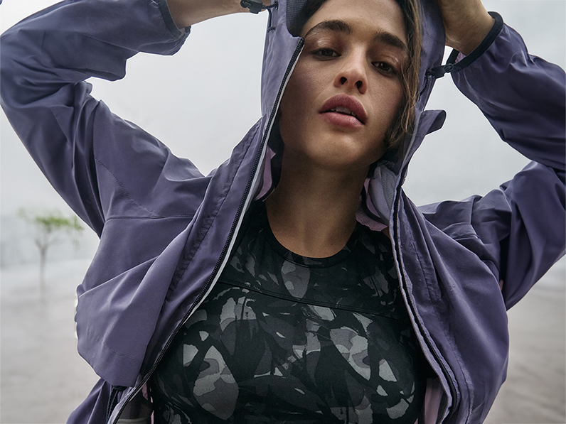 Woman wearing purple anorak and black patterned sports top