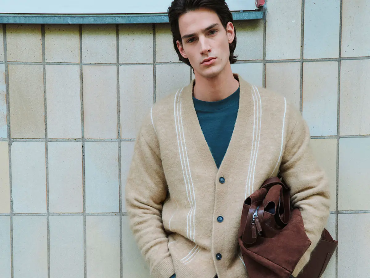 Man wearing neutral cardigan layered over teal blue top 