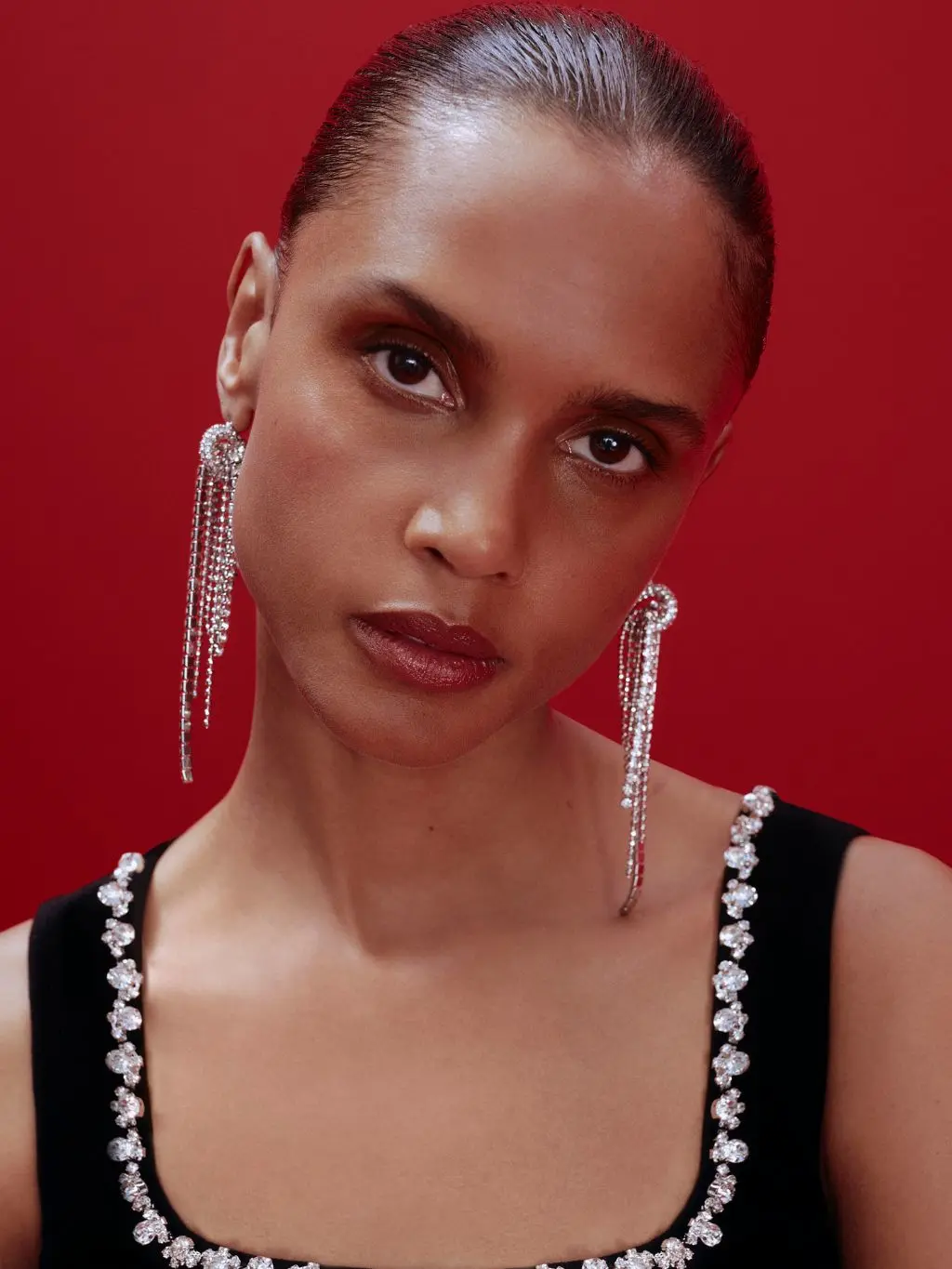A woman has smokey eye makeup, red lips and wears statement earrings