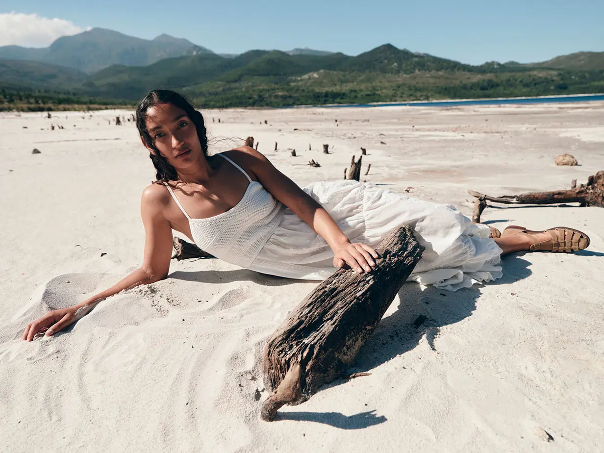 Woman in white dress lying on sandy beach