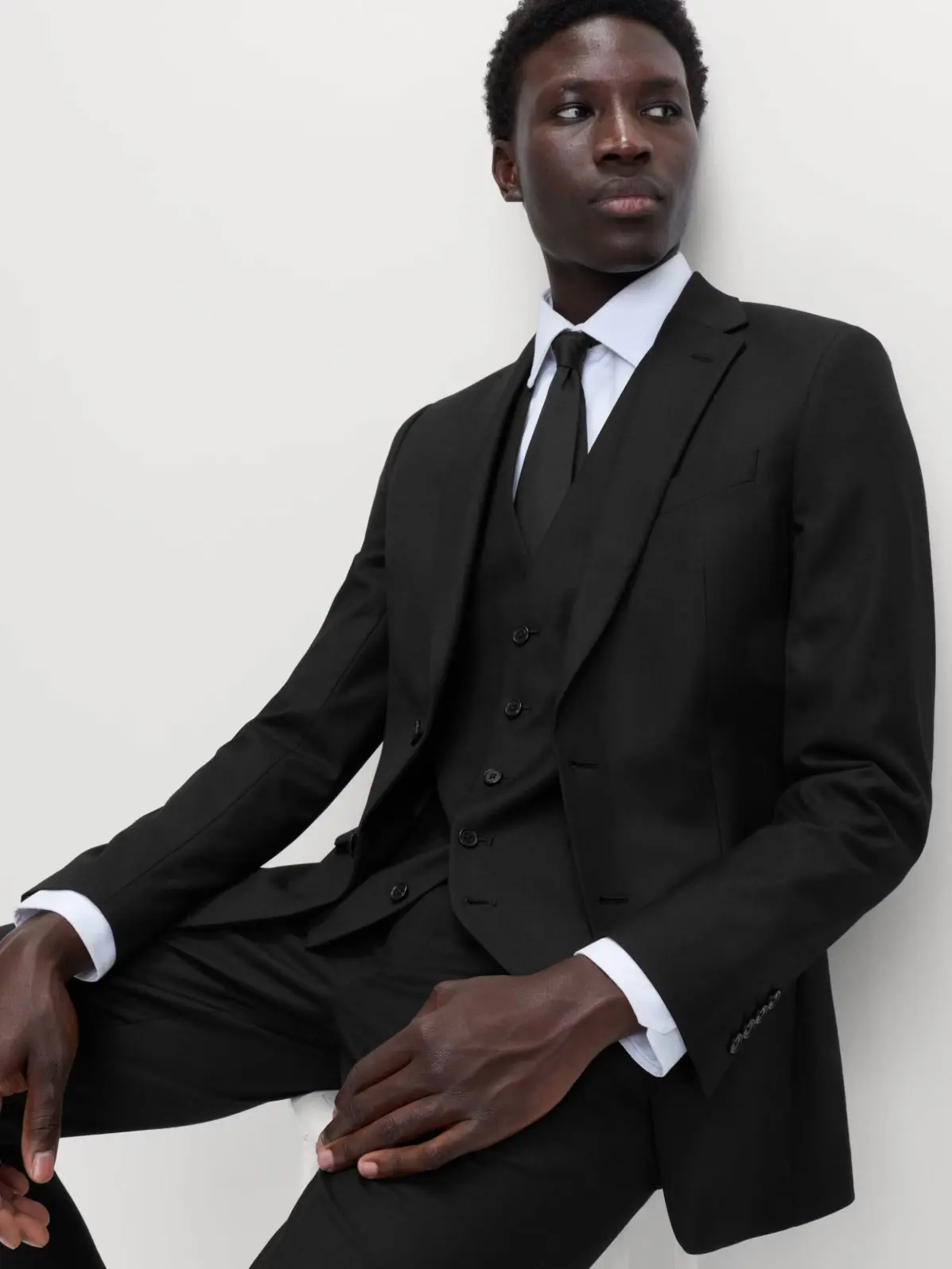 Man wearing black suit, with a white shirt and black tie 