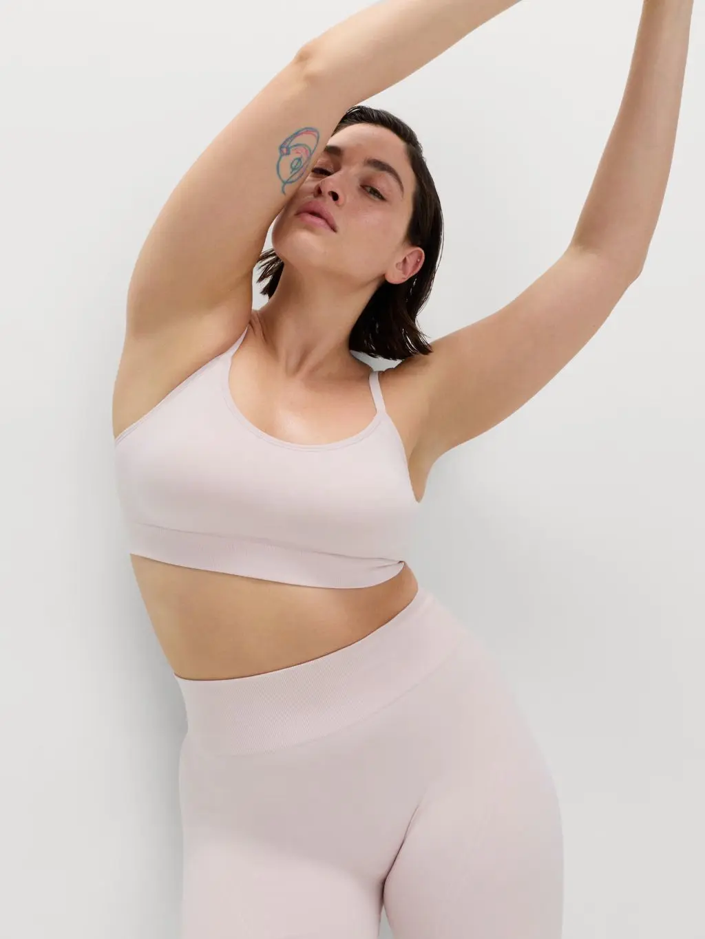 A woman wears a pale pink sports bra and matching cycling shorts