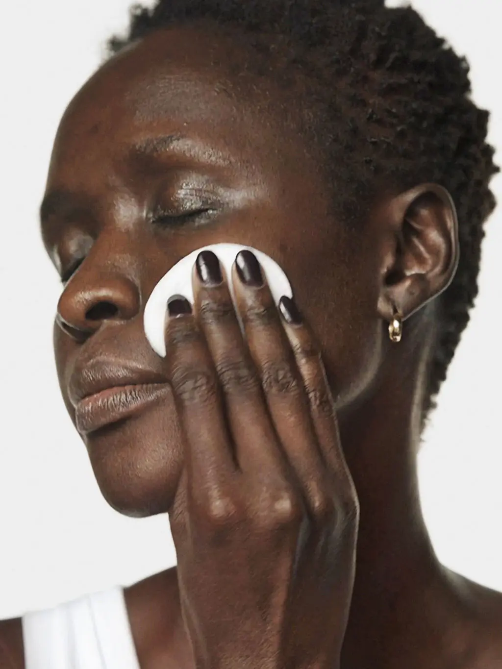 Woman using a cotton pad to apply skincare