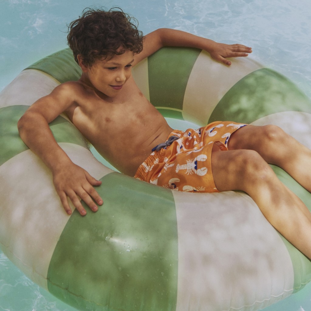 A boy wearing a shorts and playing in swimming pool. Shop now